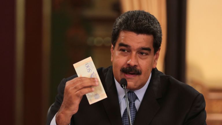 Venezuela's President Nicolas Maduro holds a bank note from the new currency Bolivar Soberano (Sovereign Bolivar)
