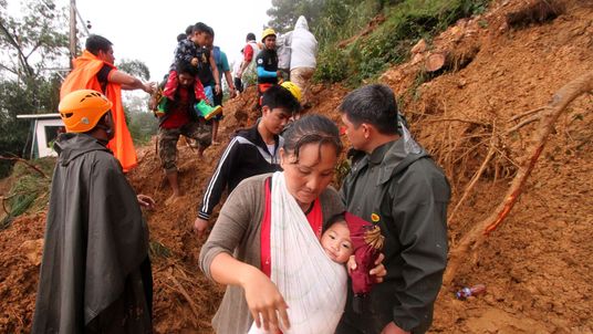 Families and relatives of miners move to safer grounds after massive landslides triggered by Super Typhoon Mangkhut in Itogon town, Benguet province on September 16, 2018. - Typhoon Mangkhut rocked Hong Kong en route to mainland China on September 16, injuring scores and sending skyscrapers swaying, after killing at least 30 people in the Philippines and ripping a swathe of destruction through its agricultural heartland. (Photo by JJ LANDINGIN / AFP) (Photo credit should read JJ LANDINGIN/AFP/Ge