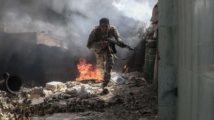 A fighter from Jaysh al Islam runs to avoid sniper fire in Douma
