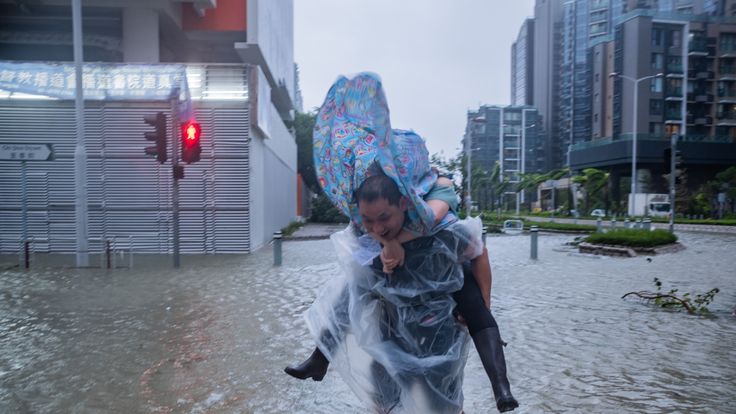 HONG KONG, HONG KONG - SEPTEMBER 16: A man carrying a woman cross a flooded road on September 16, 2018 in Hong Kong, Hong Kong. City officials raised the storm alert to T10, it&#39;s highest level,as Typhoon Mangkhut landed on Hong Kong. The strongest tropical storm of the season so far with winds as fast as 200 kilometres per hour, Mangkhut has reportedly killed at least 25 people in the Philippines as it continues it&#39;s path towards southern China. (Photo by Lam Yik Fei/Getty Images)
