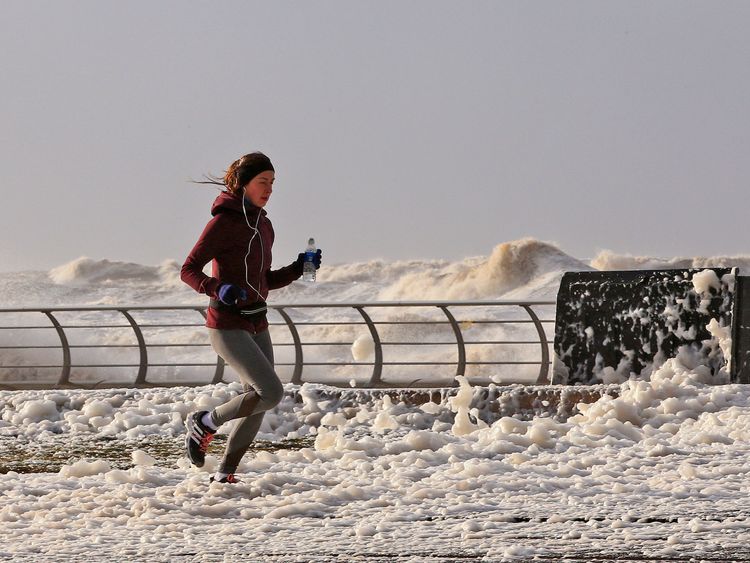 A woman jogs through sea foam in Blackpool as Storm Eleanor lashed the UK