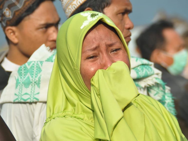 A woman cries as people look at the damages after an earthquake and a tsunami hit Palu