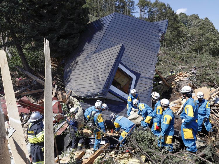 Rescue workers search for survivors from a house damaged by a landslide in Atsuma