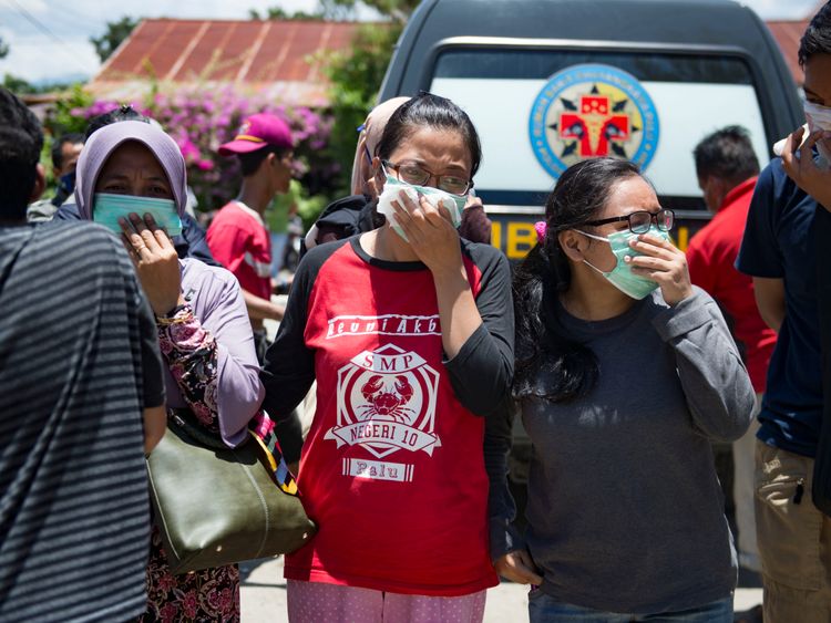 People wear masks as they attempt to identify the bodies of their relatives at the compounds of a police hospital