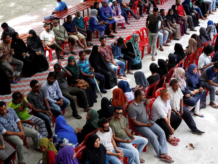 People sit in line as they wait to cast their votes at a polling station during the presidential election in Male, Maldives September 23, 2018