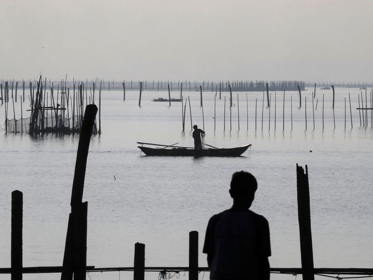 A worker recovers net in a fish pen in Luzon before the arrival of the typhoon