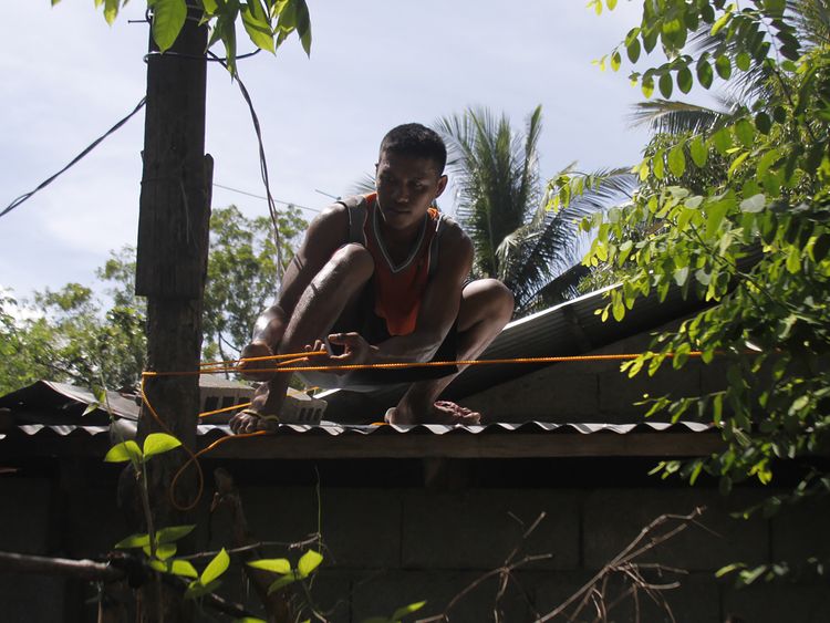 A man secures the roof of his house in Candon City, north of Manila