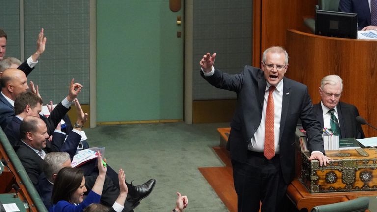 Australian PM Scott Morrison and colleagues raise their hands during question time