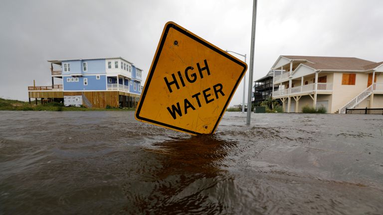 Flood waters lap at a high water warning sign that was partially pushed over by Hurricane Florence on Oak Island, North Carolina