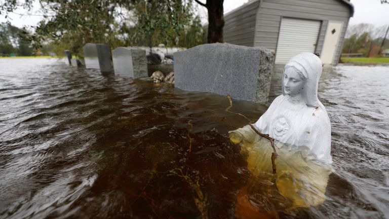 A Christian statuette is partially submerged in rising flood waters inundating a cemetery in the aftermath of Hurricane Florence, in Leland, North Carolina