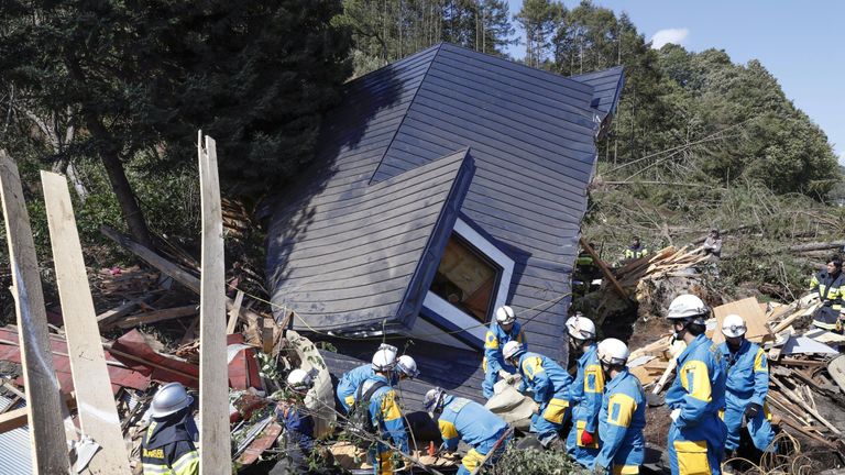 Rescue workers search for survivors from a house damaged by a landslide in Atsuma