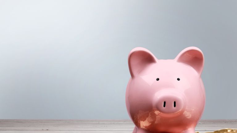 Pink piggy bank and coins on background
