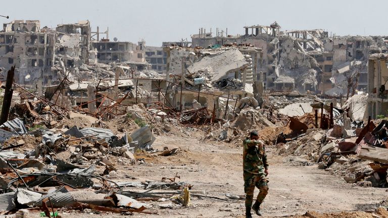 A Syrian regime member walks amid the destruction in Eastern Ghouta in April 2018