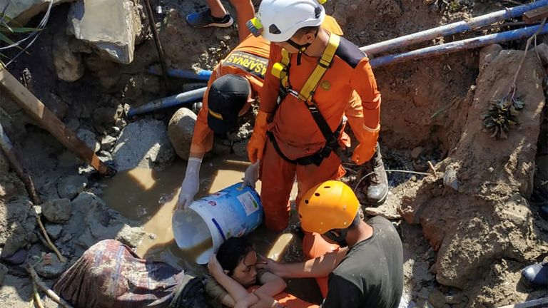 Search and rescue workers help rescue a person trapped in rubble following the disaster