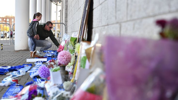 A man and a girl add to flowers and Leicester City scarfs left as tributes