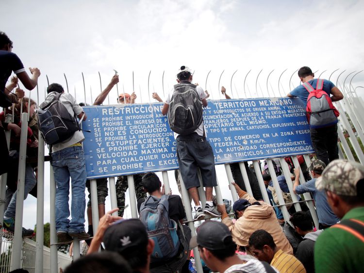 A group attempt to scale a fence into Mexico