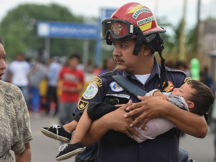 A Guatemalan firefighter carries a child