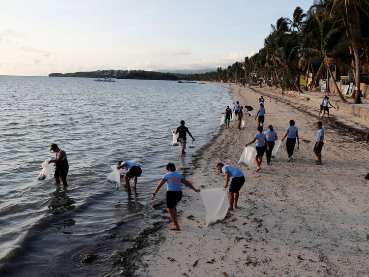 Policeman picking up rubbish on Bulabog beach on Boracay