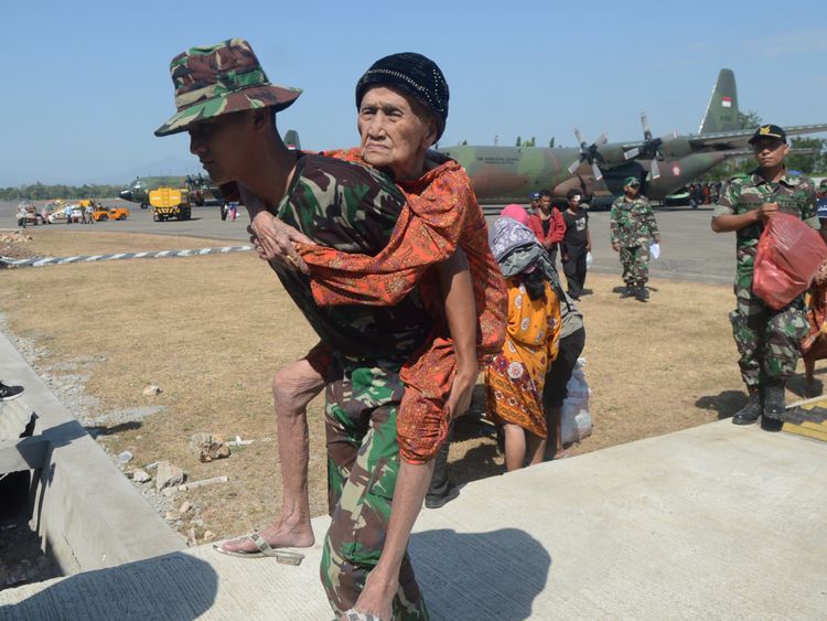 Indonesian soldiers carry an elderly woman evacuated after an earthquake and tsunami hit Palu