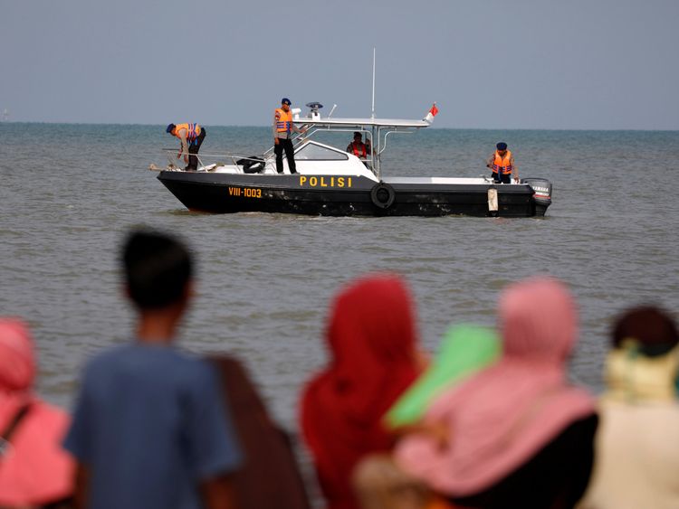 People watch rescue team members on a boat before they head to the Lion Air, flight JT610, sea crash location