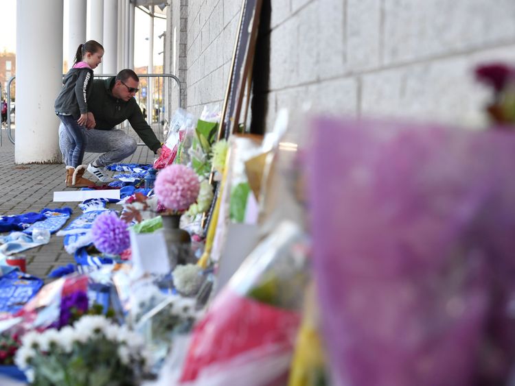 A man and a girl add to flowers and Leicester City scarfs left as tributes 