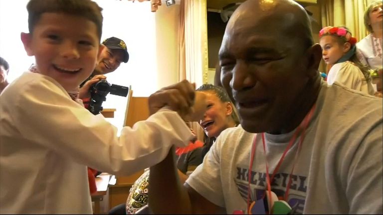 Former boxing world champion arm wrestles with a boy while visting Children&#39;s home.