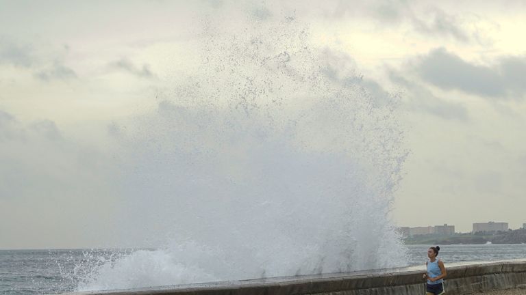 A woman jogs with a dog as waves splash at the seafront in Havana, after Hurricane Michael passed in western Cuba, October 9, 2018