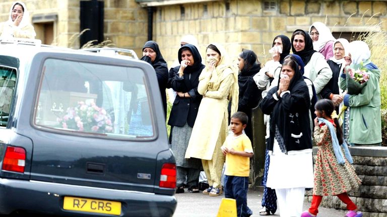 Mourners watch hearses carrying the Chishti family in 2002