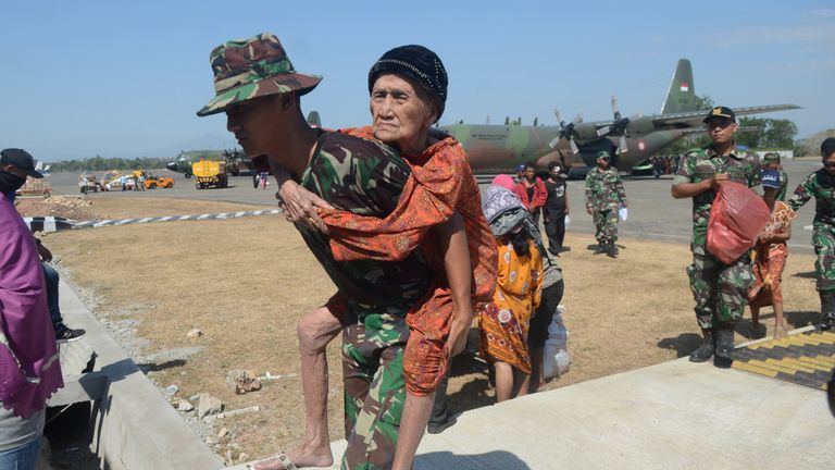 Indonesian soldiers carry an elderly woman evacuated after an earthquake and tsunami hit Palu