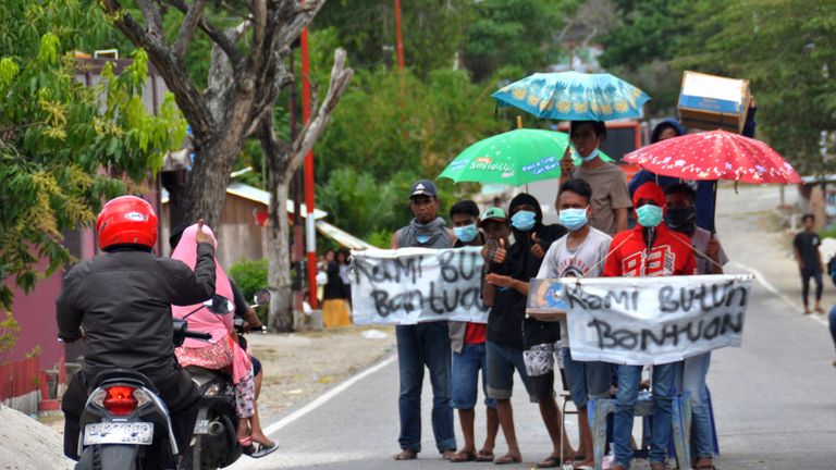 People hold signs asking for help after their homes were destroyed
