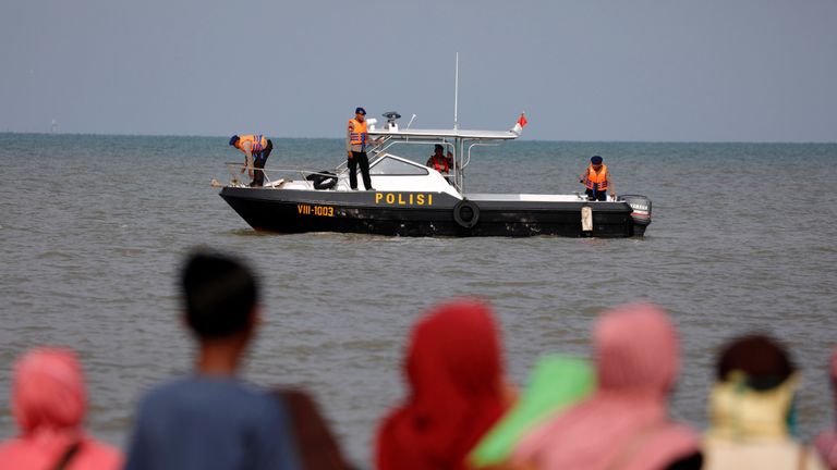 People watch rescue team members on a boat before they head to the Lion Air, flight JT610, sea crash location