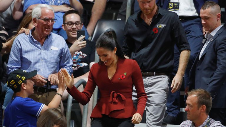 Meghan, Duchess of Sussex, gives a spectator a high five as she walks to her seat with Britain's Prince Harry to watch the Invictus Games Sydney 2018 wheelchair basketball gold medal match at Quaycentre in Sydney, Australia October 27, 2018