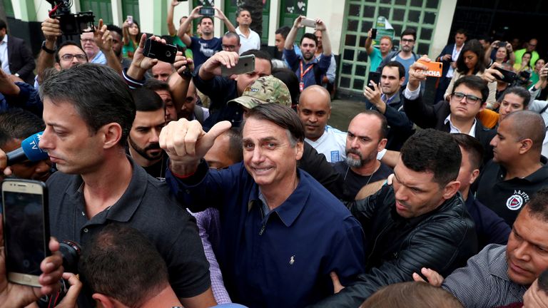 Jair Bolsonaro, pictured centre after casting his vote, was stabbed while campaigning