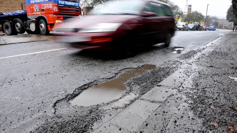 A car drive around a pothole on Broomhill Road, Bristol.
