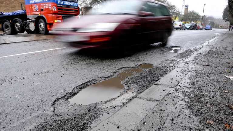 A car drive around a pothole on Broomhill Road, Bristol.
