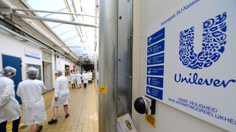 A picture taken on June 5, 2015 shows employees walking pass the logo of Unilever at the headquarters in Rotterdam