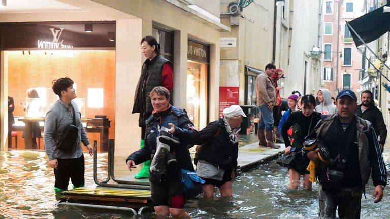 Tourists walk in the flooded streets of Venice during a high-water (Acqua Alta) alert