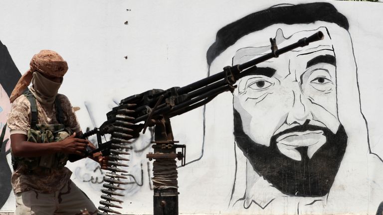 A pro-government soldier passing by a mural of the late UAE founder Sheikh Zayed bin Sultan al-Nahyan in the city of Mukalla
