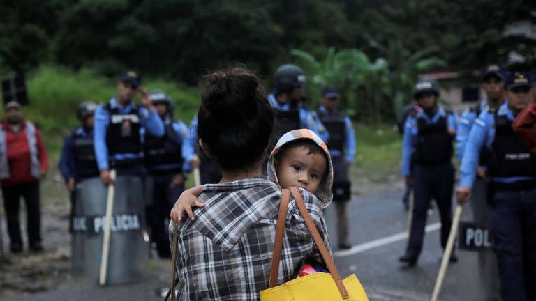 Honduran police officers stand as an Honduran migrant looks on while hoping to cross into Guatemala and join a caravan trying to reach the US