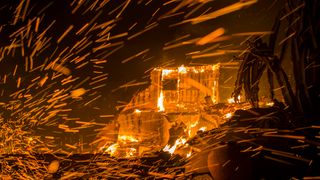 Strong winds blow embers from burning houses during the Woolsey Fire on November 9, 2018 in Malibu, California