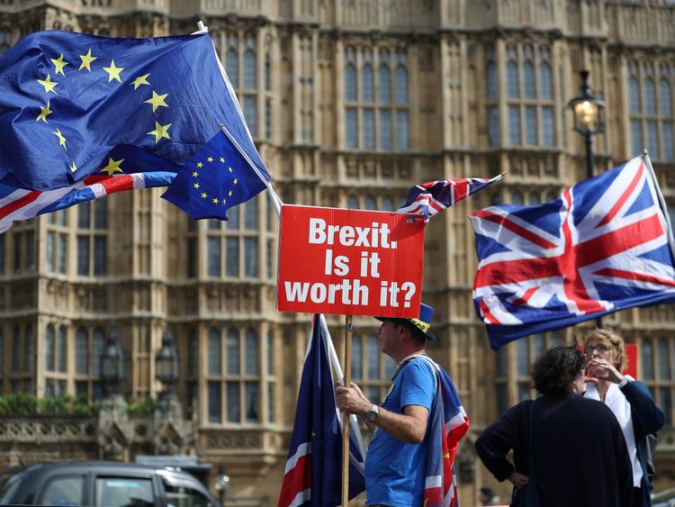 A demonstrator holds a sign that reads 'Brexit. Is it worth it?' whilst draped in European Union (EU) and Union flags, as he protests outside the Houses of Parliament in central London on September 10, 2018