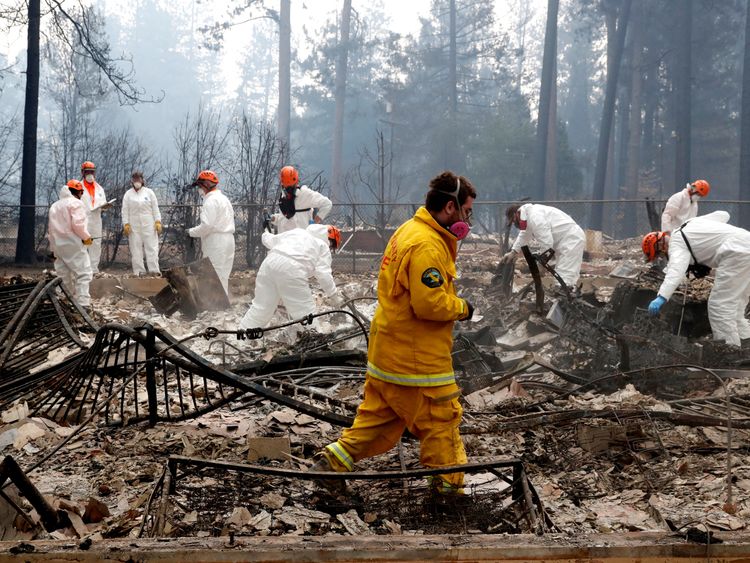 Firefighters and members of a volunteer search and rescue crew approach a house destroyed by the Camp Fire in Paradise, California, U.S., November 13, 2018. REUTERS/Terray Sylvester