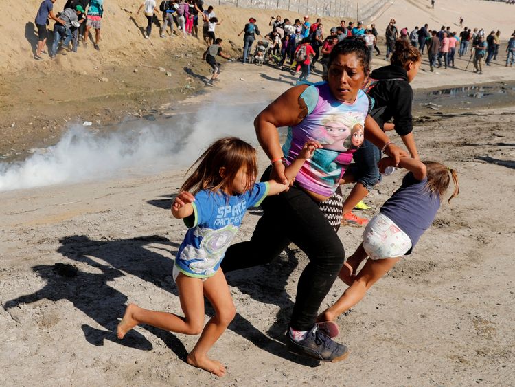 A migrant family from Honduras, runs from tear gas released by U.S. border patrol near the fence between Mexico and the United States in Tijuana