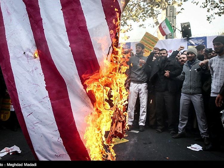 Iranian people burn the U.S. flag as they mark the anniversary of the seizure of the U.S. Embassy