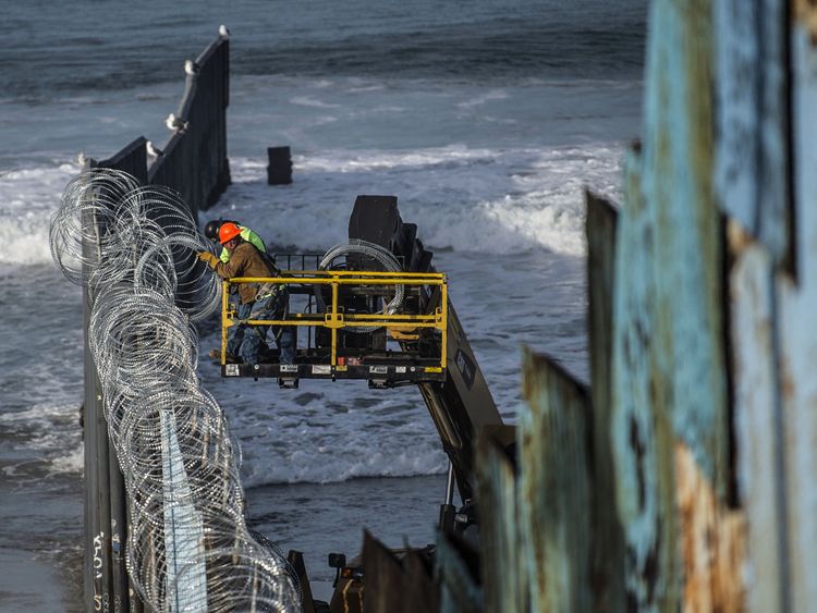 Workers on the US side of the Mexico border erect razor wire to stop the migrant caravan