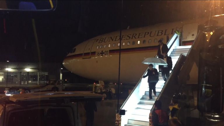 Angela Merkel, carrying an umbrella, disembarks from the plane after a fault