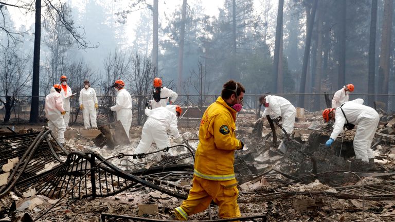 Firefighters and members of a volunteer search and rescue crew approach a house destroyed by the Camp Fire in Paradise, California, U.S., November 13, 2018. REUTERS/Terray Sylvester