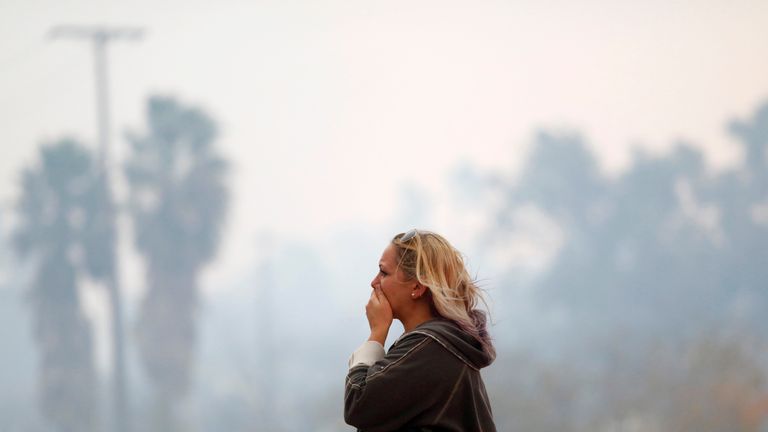 A woman reacts as the Woolsey Fire burns in Malibu, California