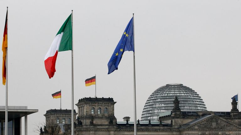 The national flags of Italy and Germany and the EU flag are pictured atop the Reichstag building
