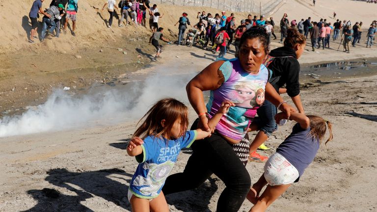 A migrant family from Honduras, runs from tear gas released by U.S. border patrol near the fence between Mexico and the United States in Tijuana